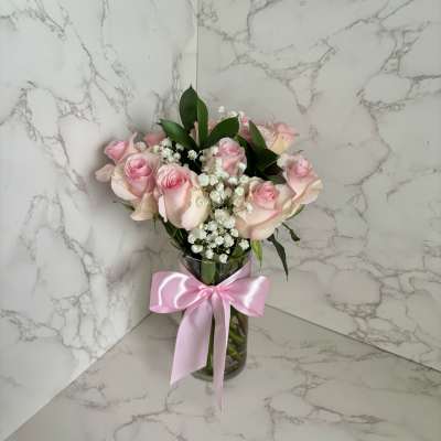 Pink roses in a glass vase with a pink ribbon