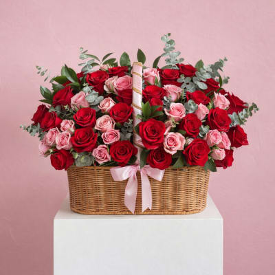 Basket arrangement of red and pink roses with a pink ribbon