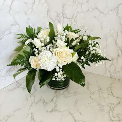 White roses and tulips arranged in a glass vase
