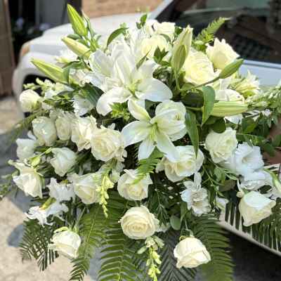 White lilies and roses arranged with fern fronds