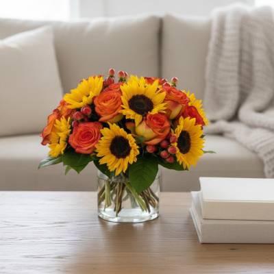 Bouquet of sunflowers and orange roses in a clear glass vase