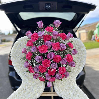 Heart-shaped floral spray with pink roses and carnations on an easel