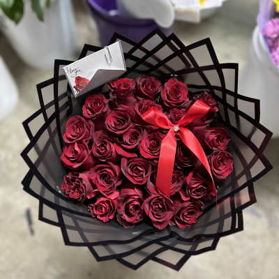 Bouquet of deep red roses wrapped in black paper with a red ribbon