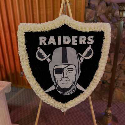 Shield-shaped floral tribute with a Raiders logo on an easel