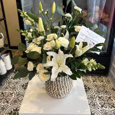 White lilies and cream roses arranged in a woven basket