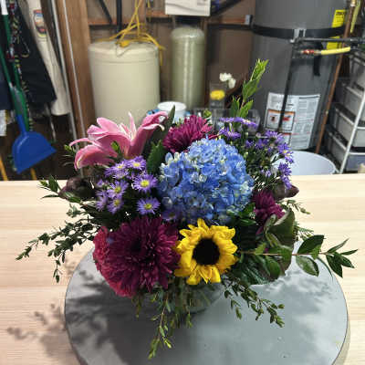 Mixed bouquet with blue hydrangea, pink lilies, purple mums, and a yellow sunflower