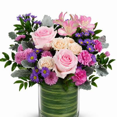 Pink and cream roses with purple daisies in a glass vase