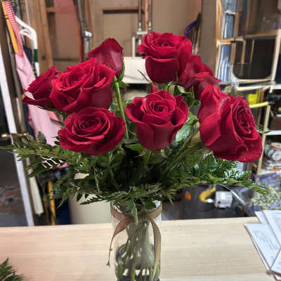 Red roses arranged in a clear glass vase with a ribbon