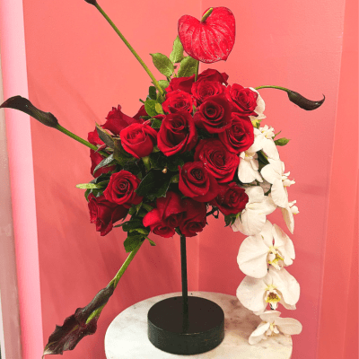 Red roses and white orchids arranged in a black vase