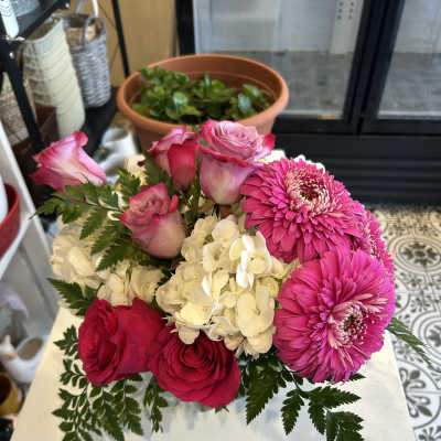 Pink roses and bright pink gerbera daisies with white hydrangea in a low bouquet
