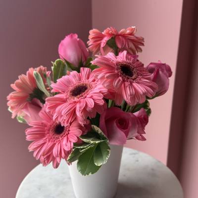 Pink gerbera daisies and roses in a white vase