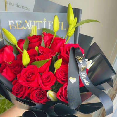 Bouquet of red roses and yellow lily buds wrapped in black paper