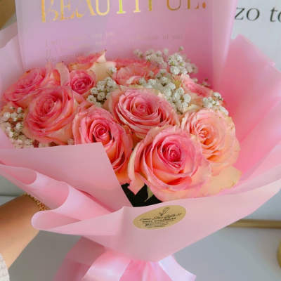 Pink rose bouquet wrapped in translucent paper with a gold "BEAUTIFUL" card