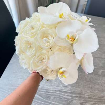 White bouquet of orchids and roses held in hand