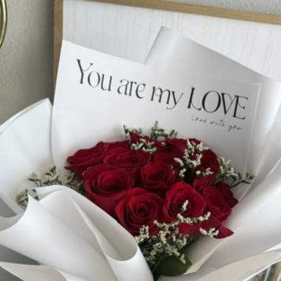 Bouquet of red roses wrapped in white paper with a love card