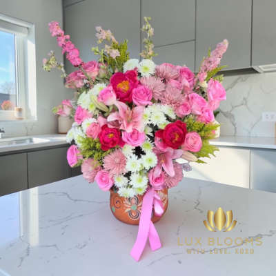 Pink and white mixed flower arrangement in a decorative vase with a ribbon