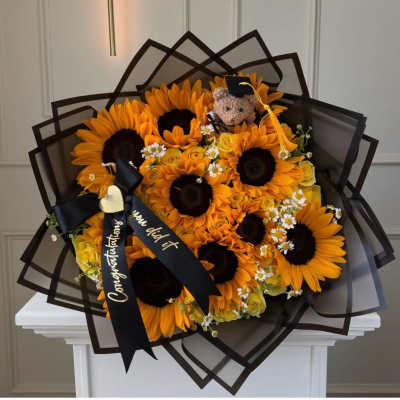 Bouquet of sunflowers and yellow roses with a graduation teddy bear