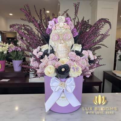 Decorative skull arrangement with purple and white flowers in a lavender box