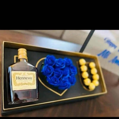 Hennessy bottle in a gift box with blue roses and yellow chocolates