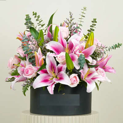 Pink lilies and roses arranged in a black box