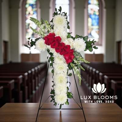 Cross-shaped floral tribute with red roses and white chrysanthemums on a stand