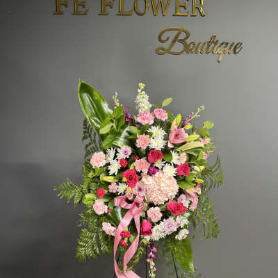 Pink and white floral standing spray with a pink ribbon on an easel