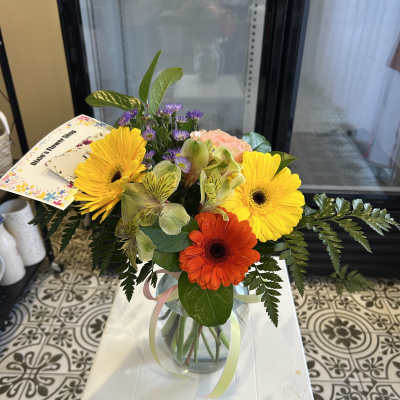 Mixed bouquet with yellow and orange gerbera daisies in a glass vase