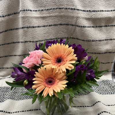 Bouquet of peach gerbera daisies and pink carnations in a glass vase
