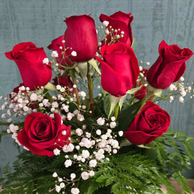 Red roses with baby's breath in a clear glass vase