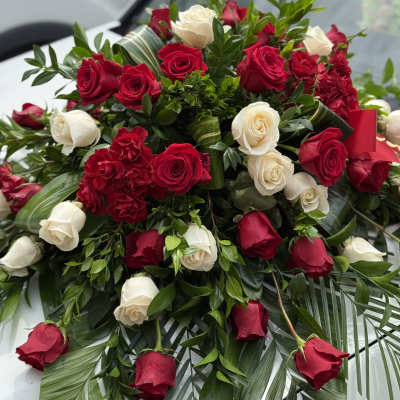 Red and white roses arranged with greenery and palm fronds