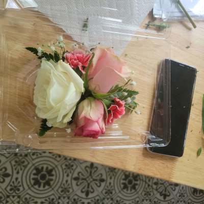 Small bouquet of pink and white roses in a clear plastic box