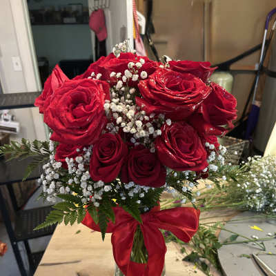 Red roses arranged in a clear glass vase with a red ribbon