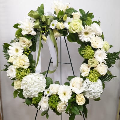 White floral wreath with roses, daisies, and hydrangeas on a stand