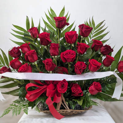Basket arrangement of red roses with a red bow and white ribbon