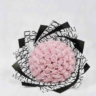 Round bouquet of pale pink roses wrapped in black-and-white paper