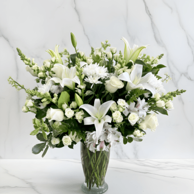 White lilies and roses arranged in a clear glass vase
