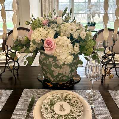 White and pink floral centerpiece in a patterned vase on a dining table