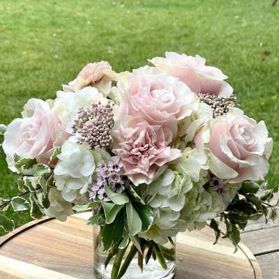 Blush roses and pale hydrangeas arranged in a clear glass vase