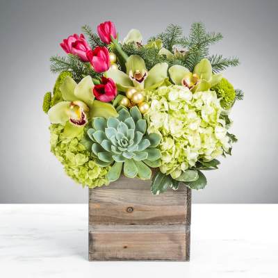 Mixed floral arrangement in a wooden box with orchids, tulips, hydrangeas, and a succulent