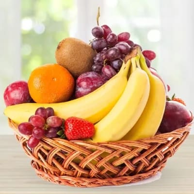 Basket of assorted fruit including bananas, grapes, oranges, kiwi, and strawberries