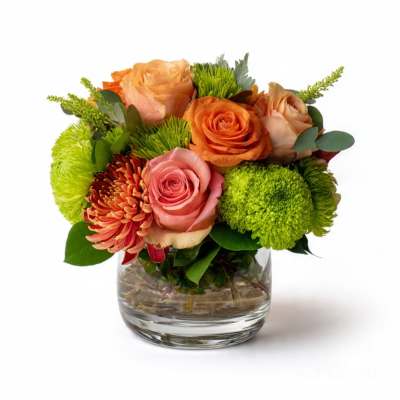 Bouquet of orange and pink roses with green mums in a glass vase