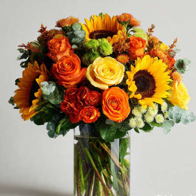 Bouquet of sunflowers and orange roses in a clear glass vase