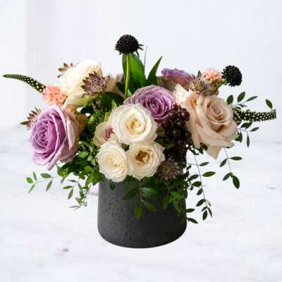 Mixed roses and small accent flowers arranged in a black vase