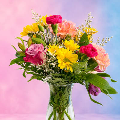 Colorful bouquet of daisies, carnations, and roses in a clear glass vase
