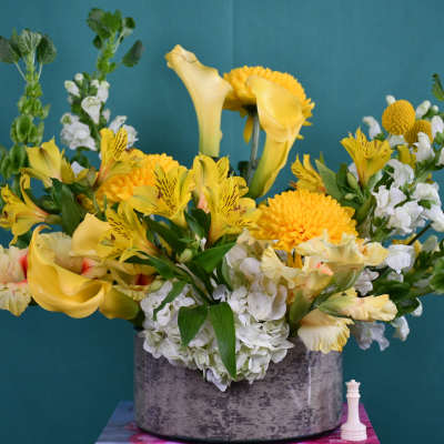 Yellow calla lilies and mixed blooms in a gray vase