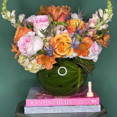 Mixed bouquet of pink, orange, and white flowers in a green vase