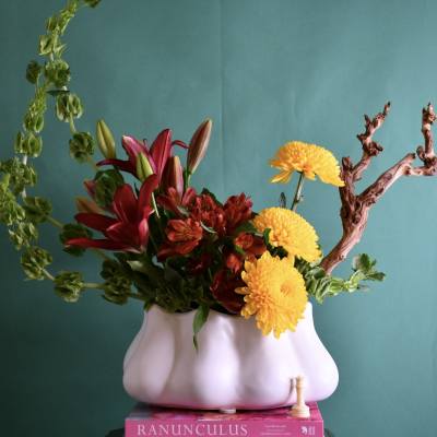 Flower arrangement in a white vase with red lilies and yellow chrysanthemums