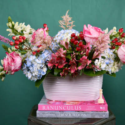 Mixed bouquet in a white ribbed vase with pink, blue, and white flowers