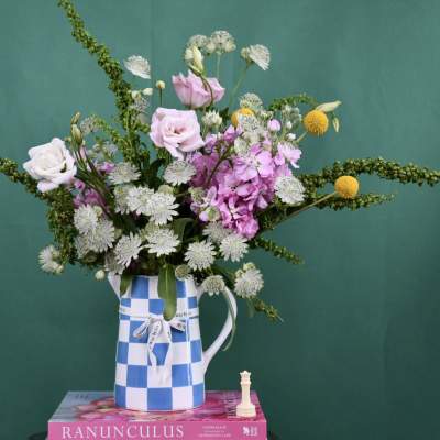 Mixed bouquet of pink and white flowers in a blue-and-white checkered pitcher