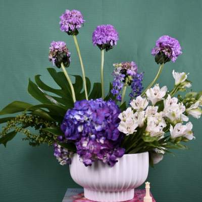 Purple and white flowers arranged in a white vase